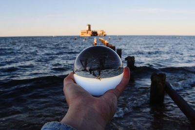 Midsection of person holding sea against sky