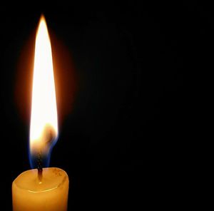 Close-up of lit candle in dark room