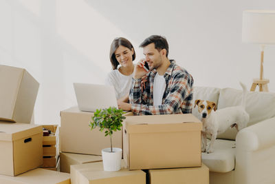 Woman sitting with man talking over smart phone in new house