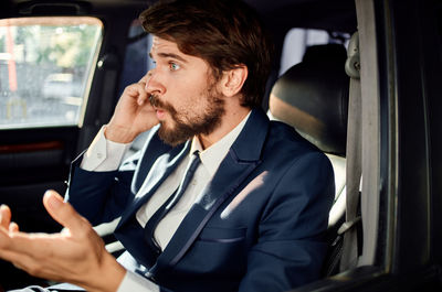 Businessman talking on phone while sitting at car