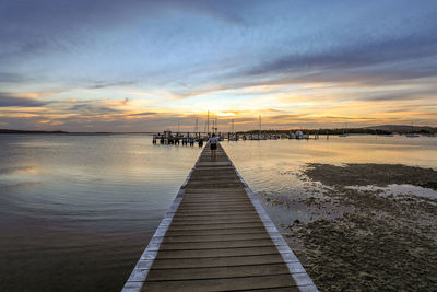 Pier over sea against sky during sunset