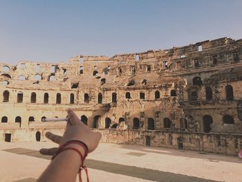 Low section of person standing by old ruin against clear sky