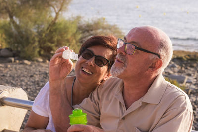 Couple blowing bubbles at beach during sunset