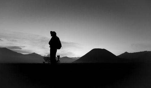 Silhouette man standing on mountain against sky