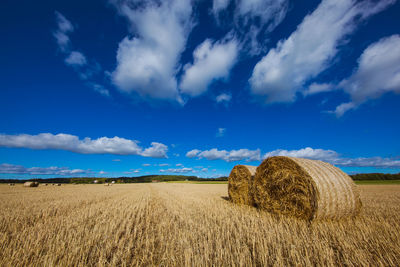 Hay bales on farm against blue sky