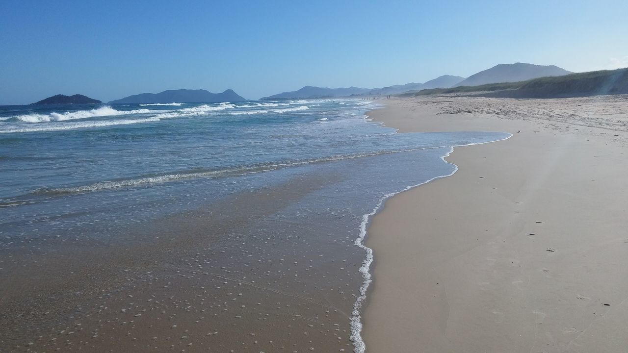 beach, sea, clear sky, tranquil scene, scenics, mountain, tranquility, sand, water, beauty in nature, shore, nature, copy space, blue, coastline, idyllic, non-urban scene, mountain range, remote, surf