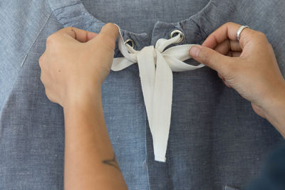 Cropped hands of woman tying knot of top