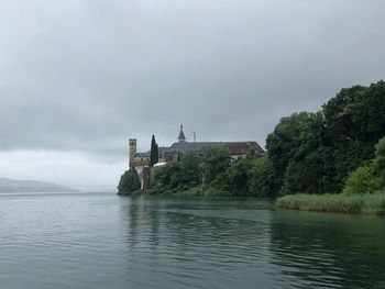 Scenic view of river by building against sky