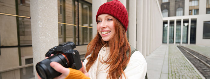 Portrait of young woman holding camera