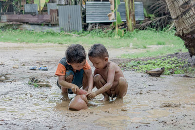 Rear view of shirtless boy on mud