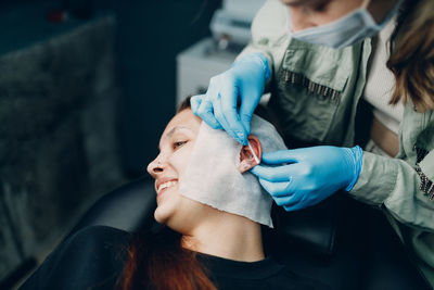 Woman piercing ear of female customer