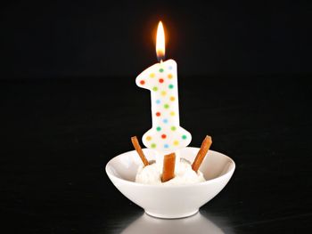 Close-up of burning candle against black background