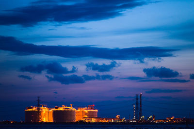 Illuminated factory against sky at night