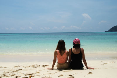 Rear view of couple sitting on beach