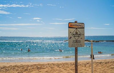 Information sign on beach against sky