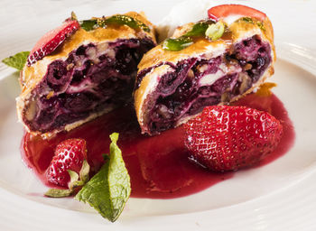 Close-up of cherry strudel served with strawberry in plate on table