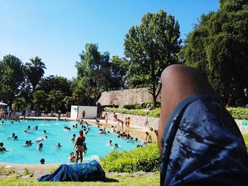 Low section of man by swimming pool against sky