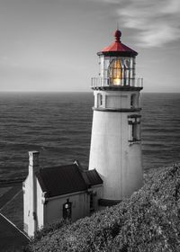 Lighthouse by sea against sky