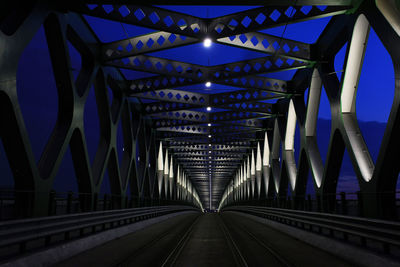 Illuminated railroad bridge against blue sky