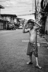 Portrait of shirtless boy standing against built structure