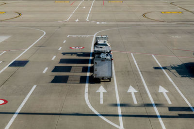 High angle view of luggage carts by arrow sign on runway