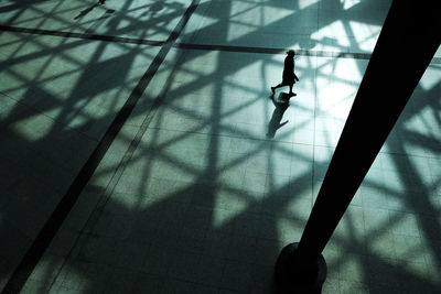 High angle view of silhouette woman walking on tiled floor