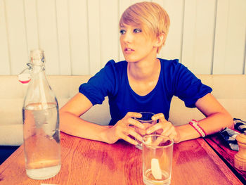 Portrait of boy with drink sitting on table