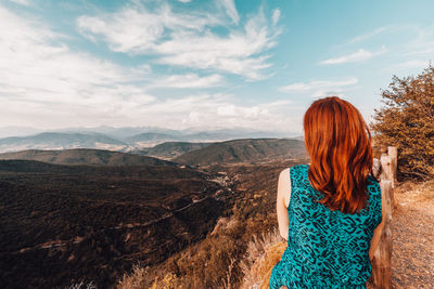 Rear view of woman looking at mountains against sky