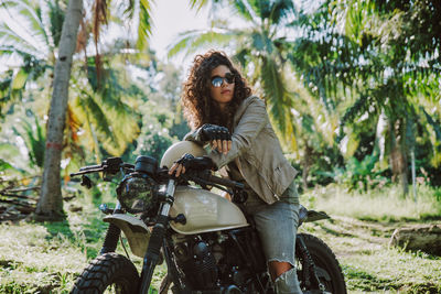 Young woman with motorcycle against trees