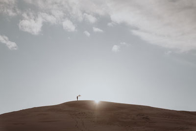 Person standing on desert land against sky