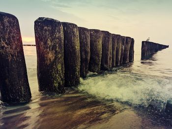 Panoramic shot of wooden post in sea against sky