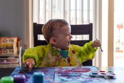 Cute girl painting on table at home