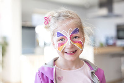 Portrait of smiling girl with painted butterfly on face