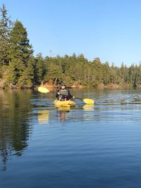 People in lake against clear sky