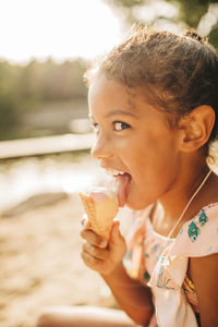Girl looking sideways while licking ice cream on sunny day