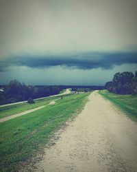 Road amidst field against sky