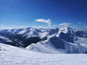 Scenic view of snowcapped mountains against blue sky