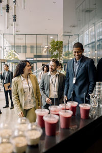 Smiling male and female business professionals walking towards bar counter at convention center