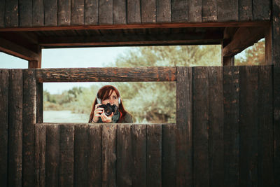 Portrait of dog sitting on wooden fence