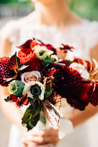 Close-up of hand holding bouquet of red roses
