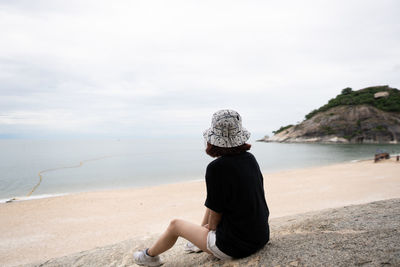 Rear view of woman sitting on beach