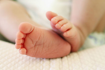 Low section of baby lying on bed