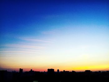 Silhouette cityscape against sky at sunset