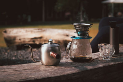 Coffee maker is placed on top of wooden chair in camping area.