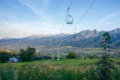 Overhead cable car over mountains against sky