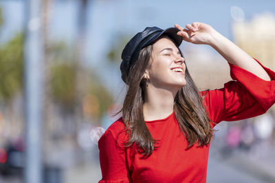 Smiling teenage girl wearing red top in city during sunny day