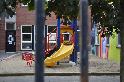 View of empty playground against trees and buildings