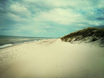 Scenic view of beach against cloudy sky