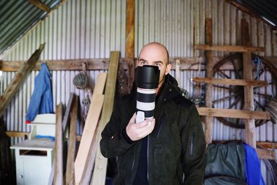 Close-up of man holding camera on face in hut