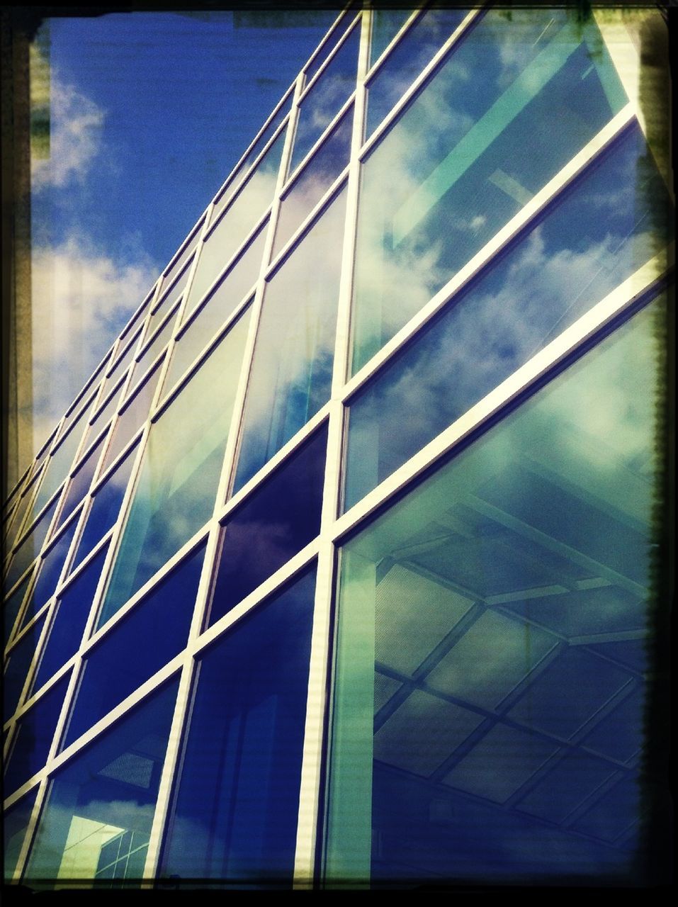 low angle view, architecture, built structure, transfer print, building exterior, glass - material, modern, auto post production filter, reflection, sky, office building, window, building, glass, city, day, blue, no people, pattern, outdoors